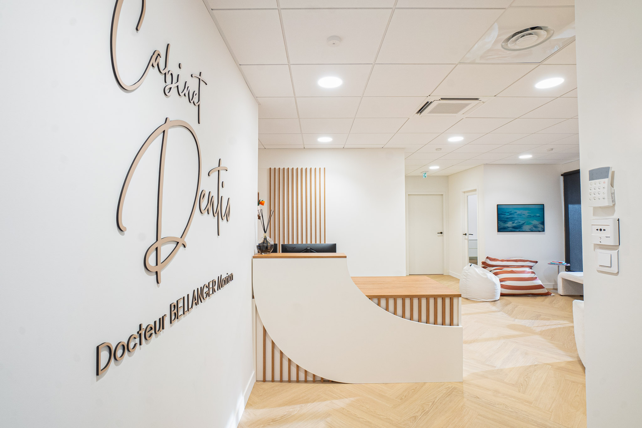 L'accueil du cabinet DENTIO à Brest, avec l'enseigne murale et la banque d'accueil en bois clair