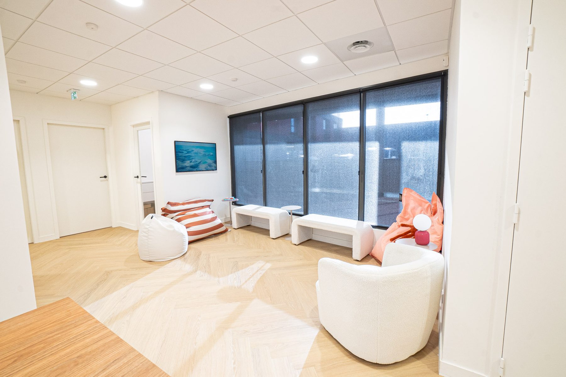 La salle d'attente du cabinet DENTIO : parquet clair, fauteuils en bouclette et poufs colorés pour les enfants