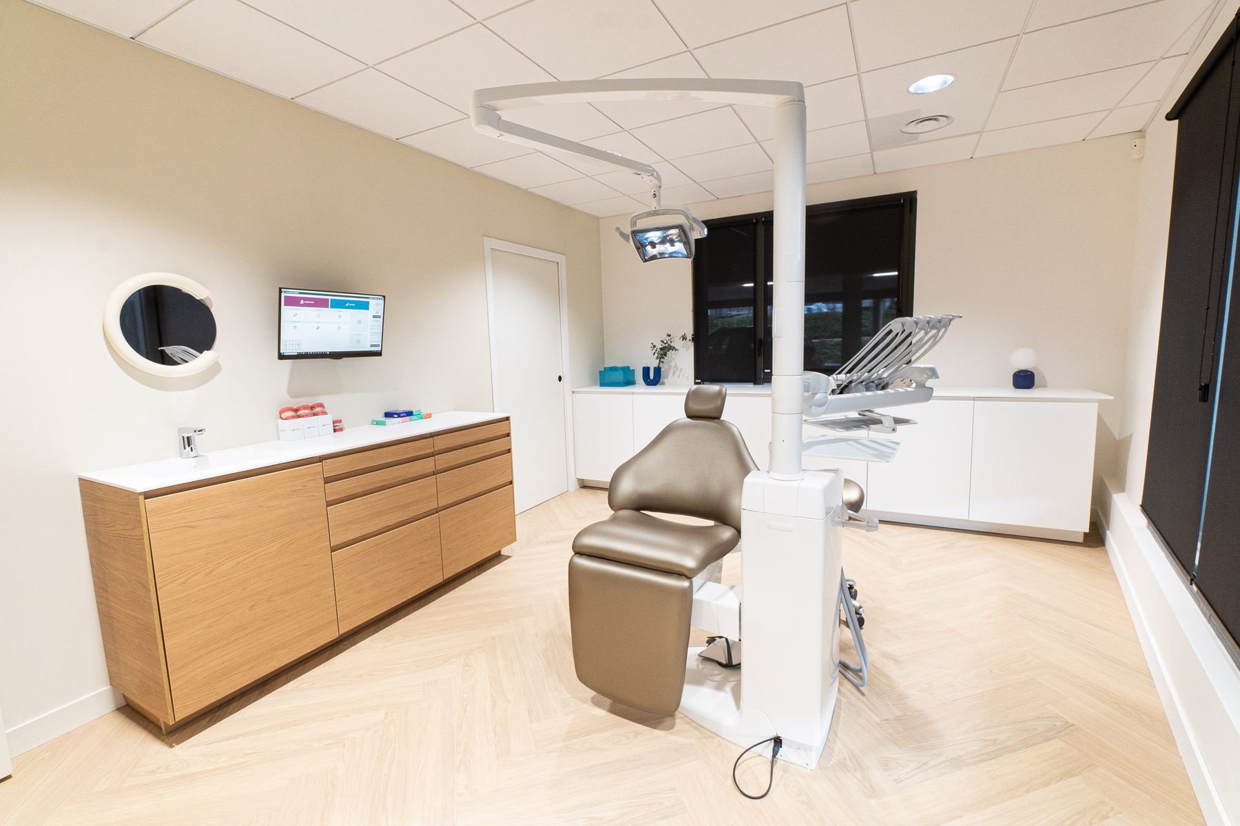 Un poste de soin du cabinet DENTIO : fauteuil, écran mural et meuble en bois clair
